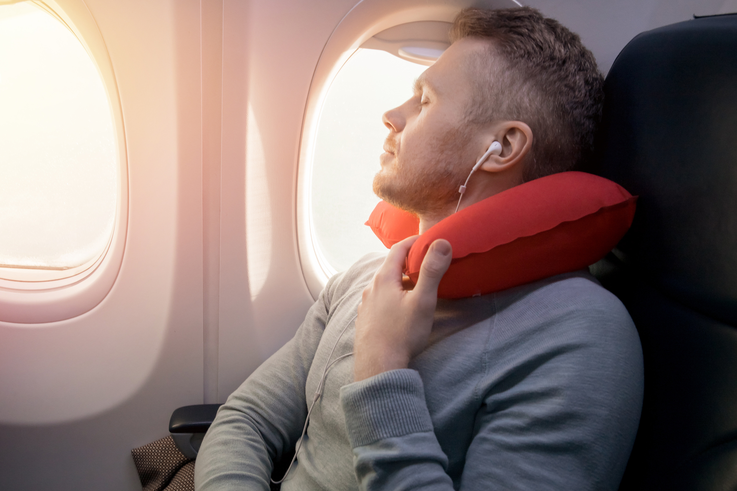Male passenger of airplane and enjoys pillow for sleeping