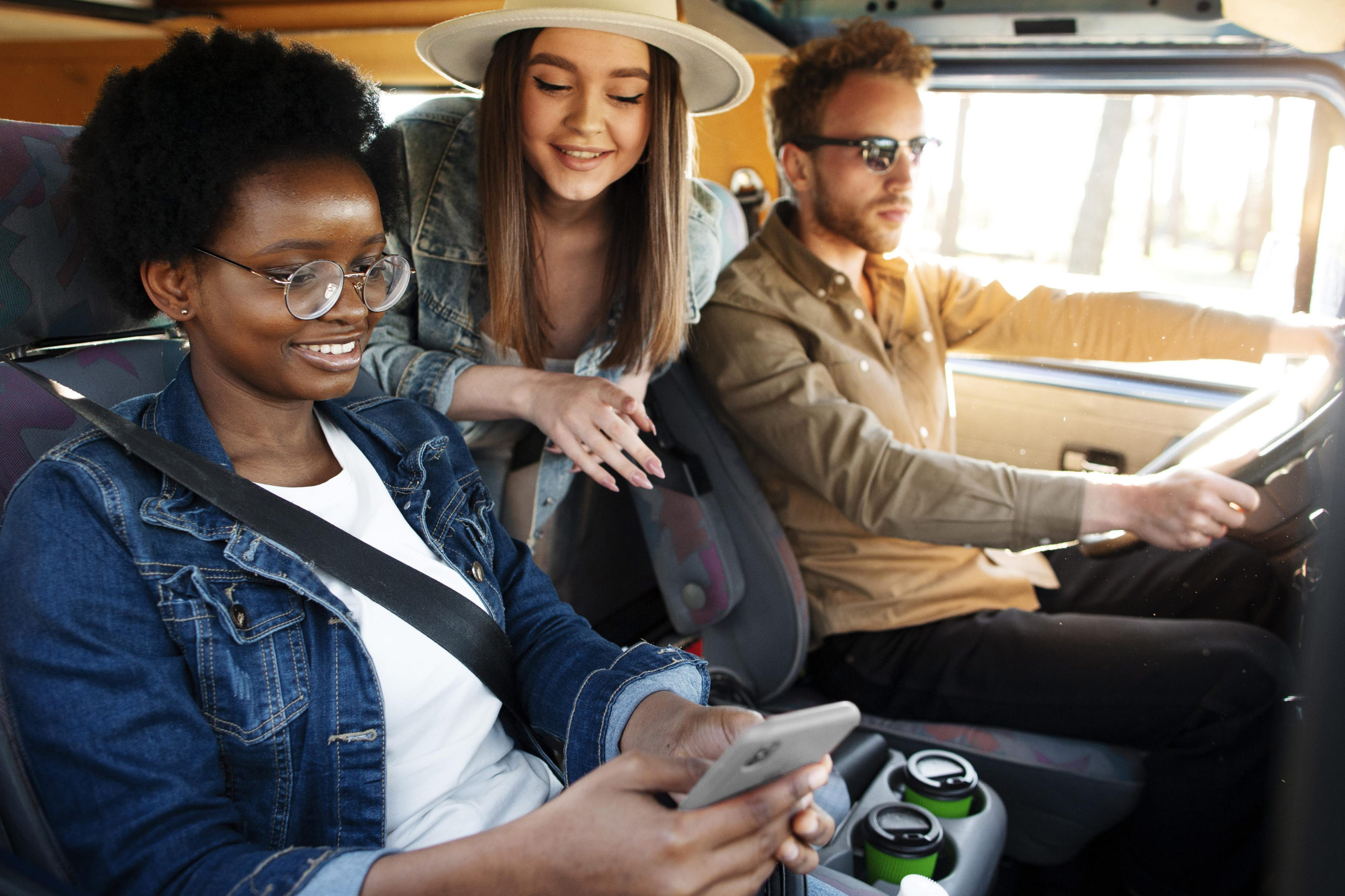 friends in a camper watch tourist content on a smartphone