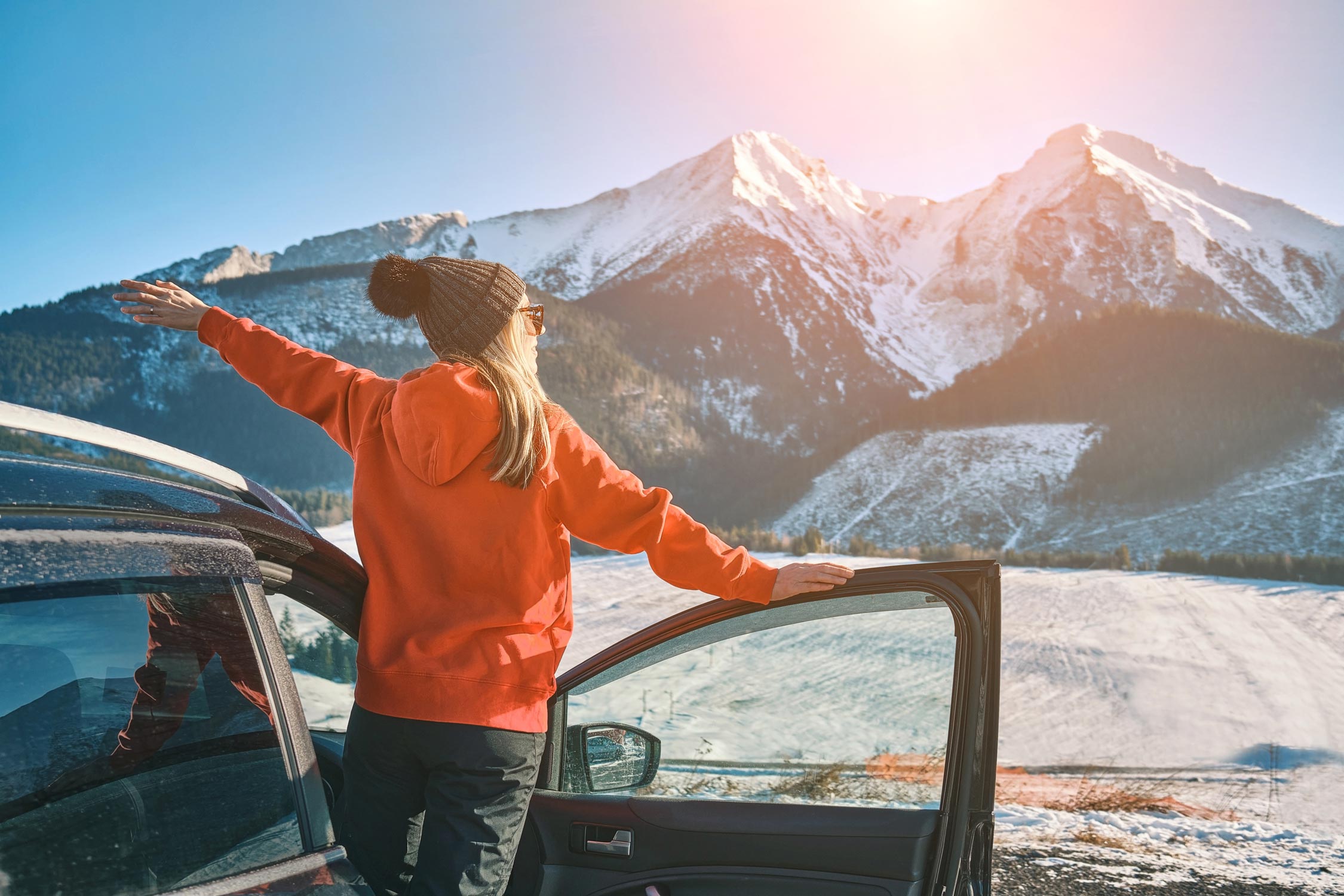 Happy Female in car enjoying winter mountain landscape