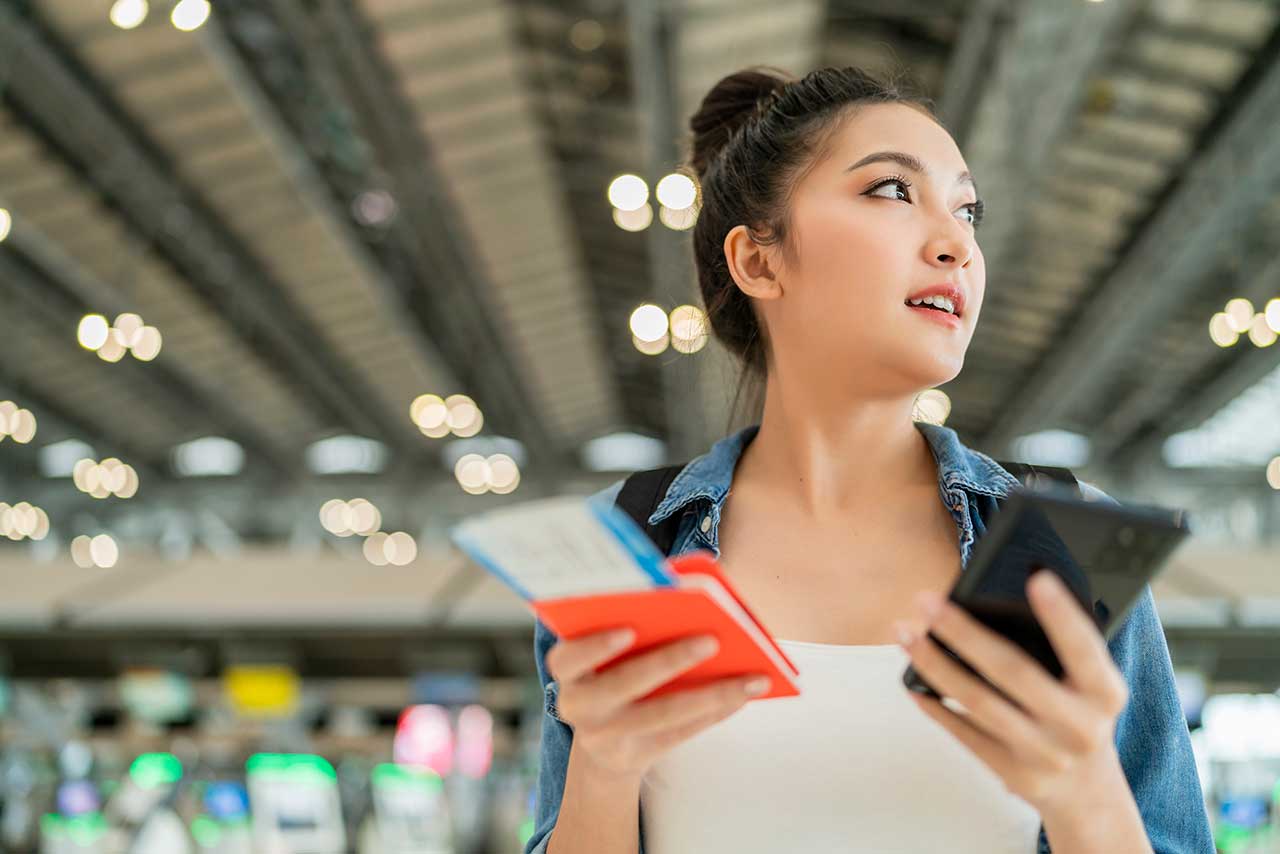 female ready to travel at airport uses her smartphone
